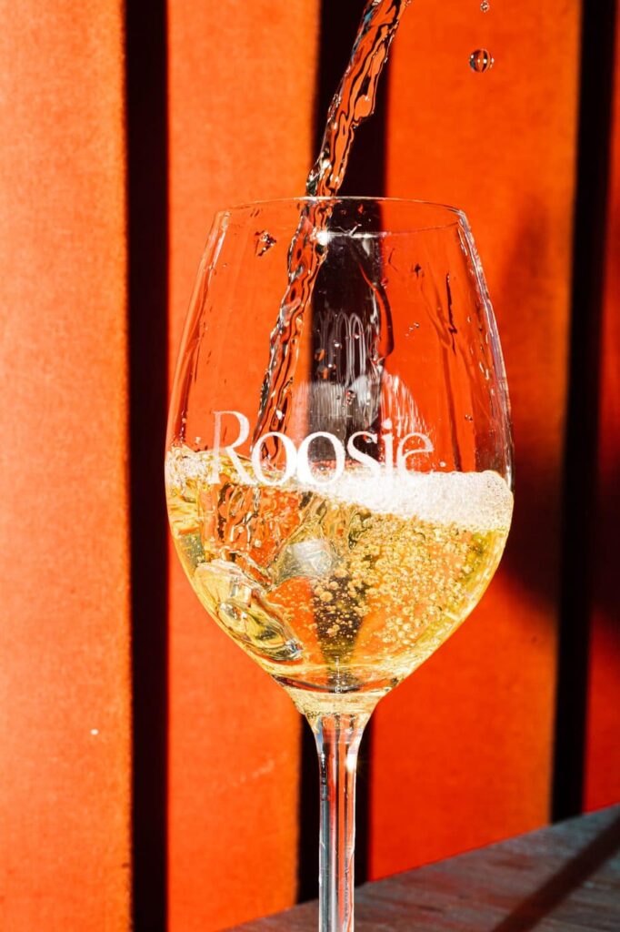 Wijnglas met het Roosje-logo wordt ingeschonken